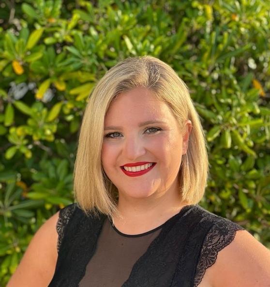 Portrait von Johanna Gfundtner, Stimmbildnerin der Jugendsingakademie Krems, vor einem grünen Blätterhintergrund. Perfekt für die Teamvorstellung auf der Webseite der Jugendsingakademie Krems, die sich auf die Förderung junger Talente im Chorgesang spezialisiert hat.